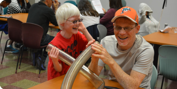 Father and son smile and laugh together as they work on a STEM project.